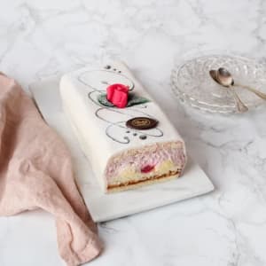 Tårtlängd med vit marsipan och ros på toppen.