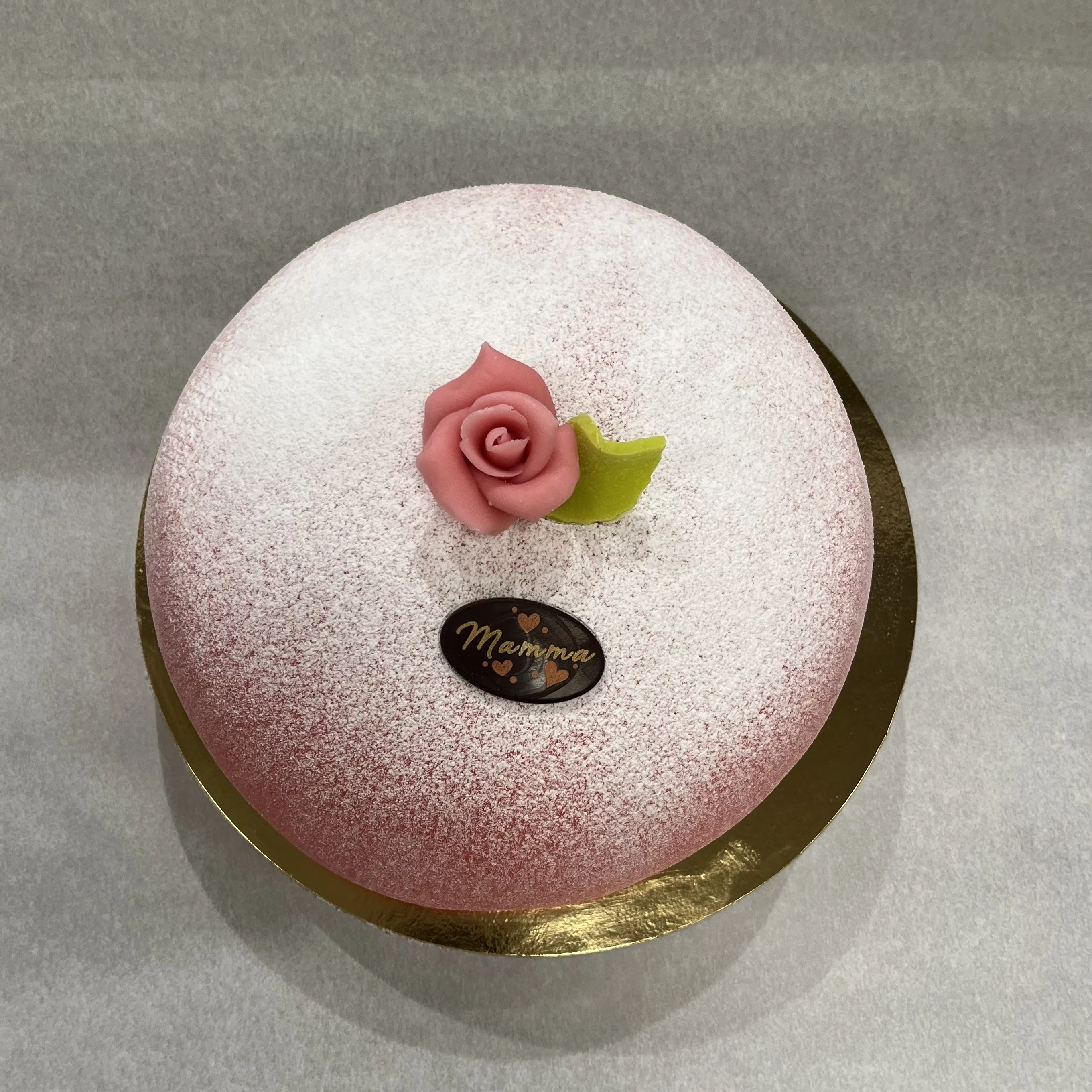 Morsdagtårta. En operatårta med hallonsylt, vaniljkräm och lättvispad grädde. Täcks med rosa marsipan.