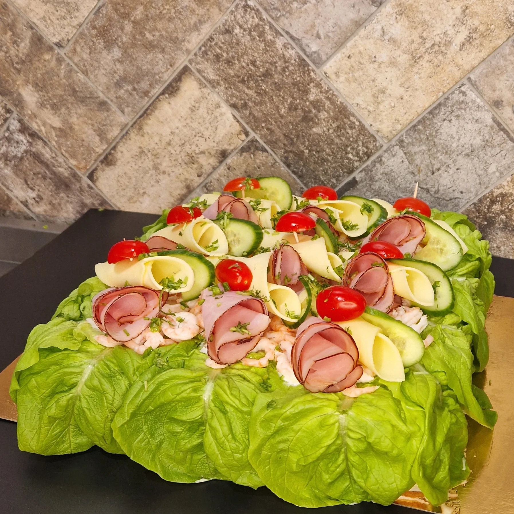 smörgåstårta med skinka och handskalade räkor. ost och skinkrullar samt krispig sallad, tomat, gurka