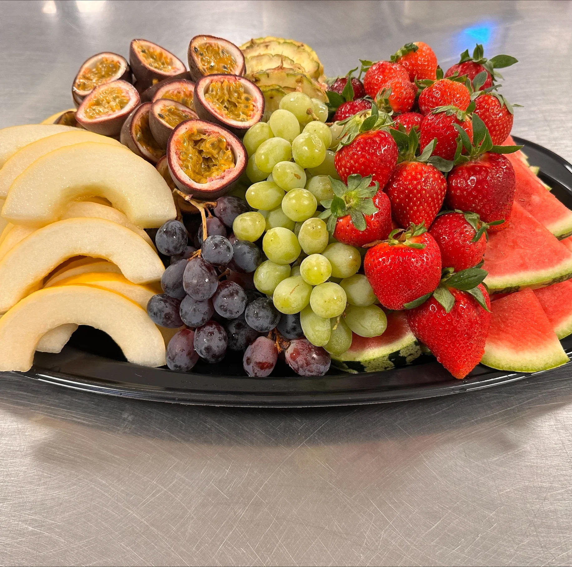 Fruktfat med melon, ananas, druvor, jordgubbar, passionsfrukt