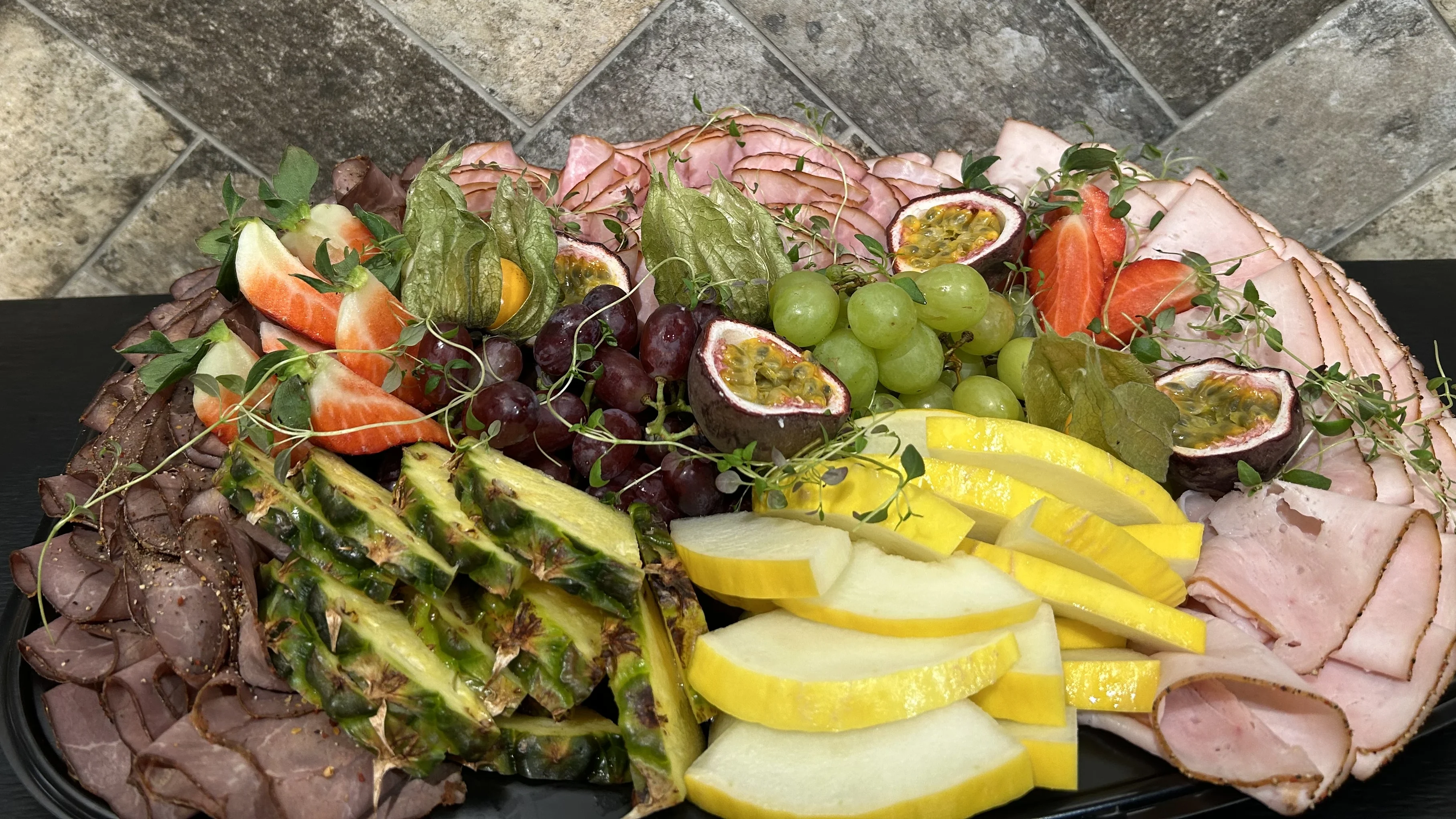 Festfat/bricka med krispiga säsongens frukter och fräscht kallskuret delikatesschark