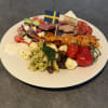 Tallrik med pastasallad, tomater, kycklingspett, kallskuret och basilkasås. toppas med en svensk flagga