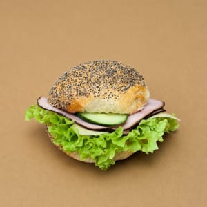 En luftig valmofralla med mild ost, rökt skinka, krispig gurka och fräsh sallad