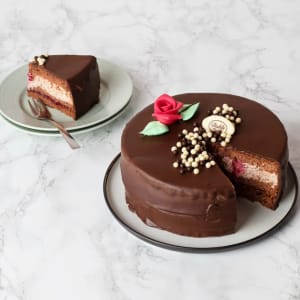 Mörk skönhet med ljuv insida. Chokladbottnar varvas med hallon och len vispgrädde. Hela härligheten täcks med ett generöst lager hemlagad mörk chokladtryffel.