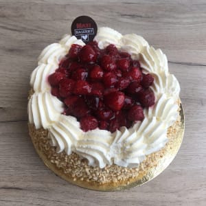 En tårta med krokantströssel runt kanterna och grädpluppar med hallon i mitten