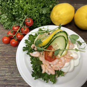 En räksmörgås garnerad med citron och gurka