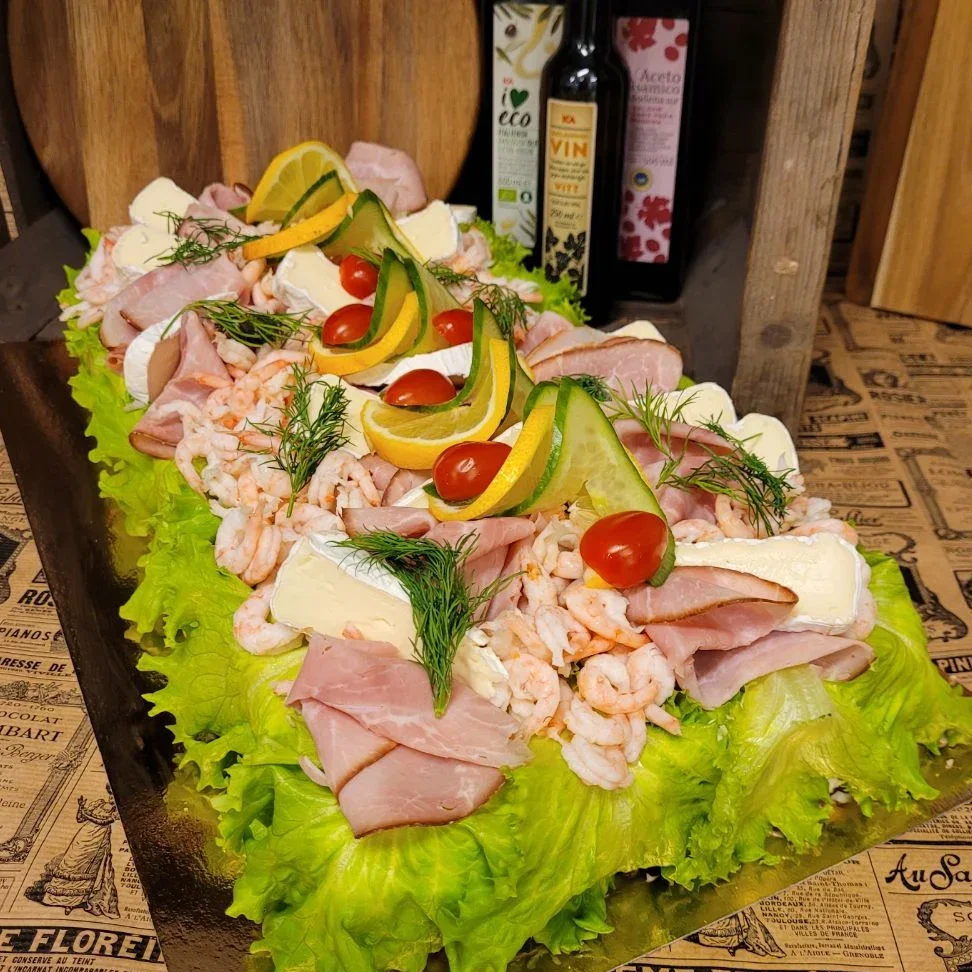 Skinksmörgåstårta fylld med vår egengjorda skinkröra, toppad med handskalade räkor, brieost, skinka och lite annat gott.  Önskar du få den utan skaldjur? Skriv det i kommentaren så löser vi det! Kostnaden för den är samma som standardportion.