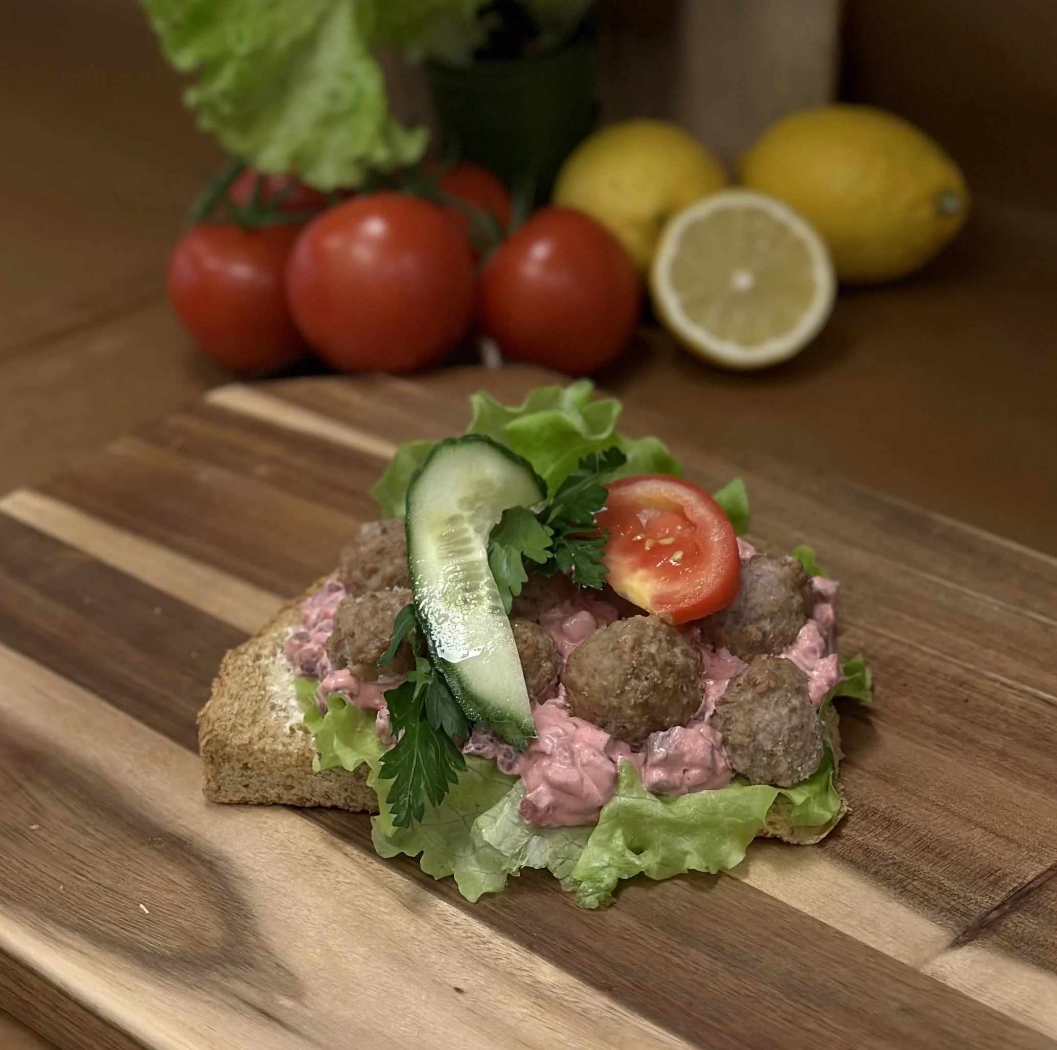 En rågsiktskaka toppad med rödbetsallad, köttbullar, plocksallat, tomat, gurka och persilja.