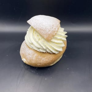 Mjuk kardemummabulle med ljuvlig vaniljfyllning och fluffig grädde toppad med florsocker.