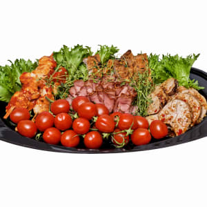 Ett grillmix fat med fem olika sorters kött och lite tomater och grönsallad för dekoration.