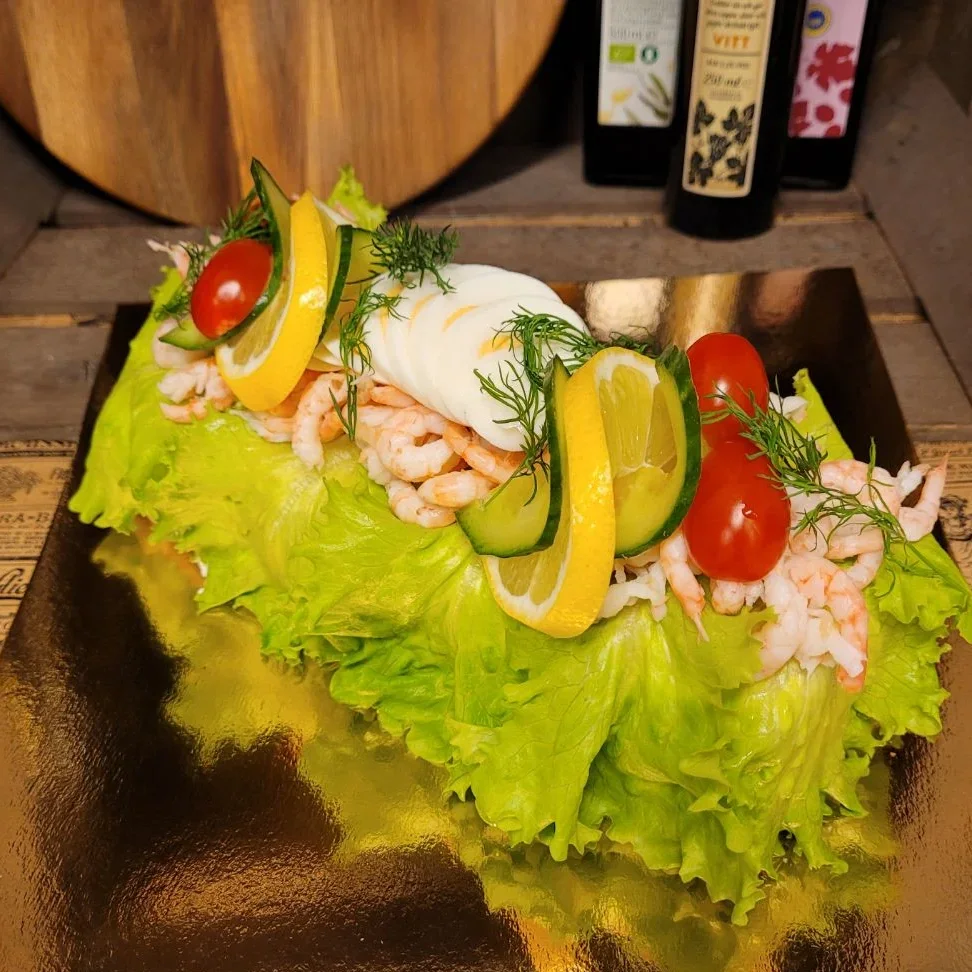Räksmörgåstårta fylld med vår egengjorda räkröra, toppad med handskalade räkor, ägg och lite annat gott.