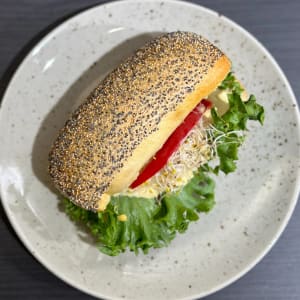 Ljus fralla toppad med vallmofrön, fylld med hummus, groddar och skivad paprika