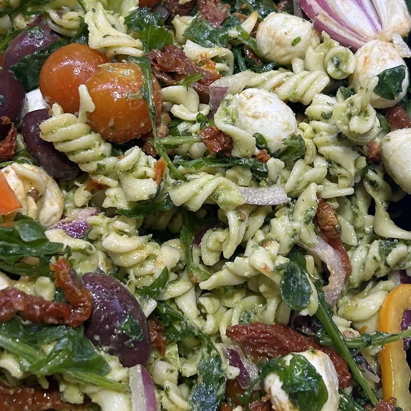 Pastasallad med pesto, mozzarella, soltorkade tomater, rödlök, paprika, babyplommontomater, ruccola och oliver.