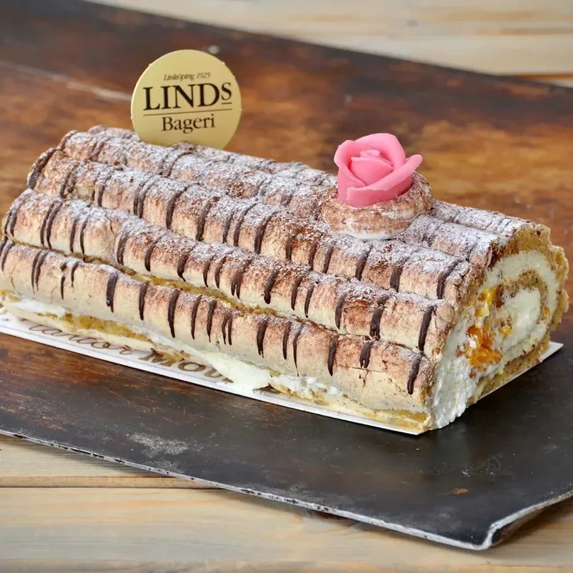 Marängbottnar med rivna hasselnötter, mandariner och grädde. Dekorerad med choklad, kakao och marsipanros.