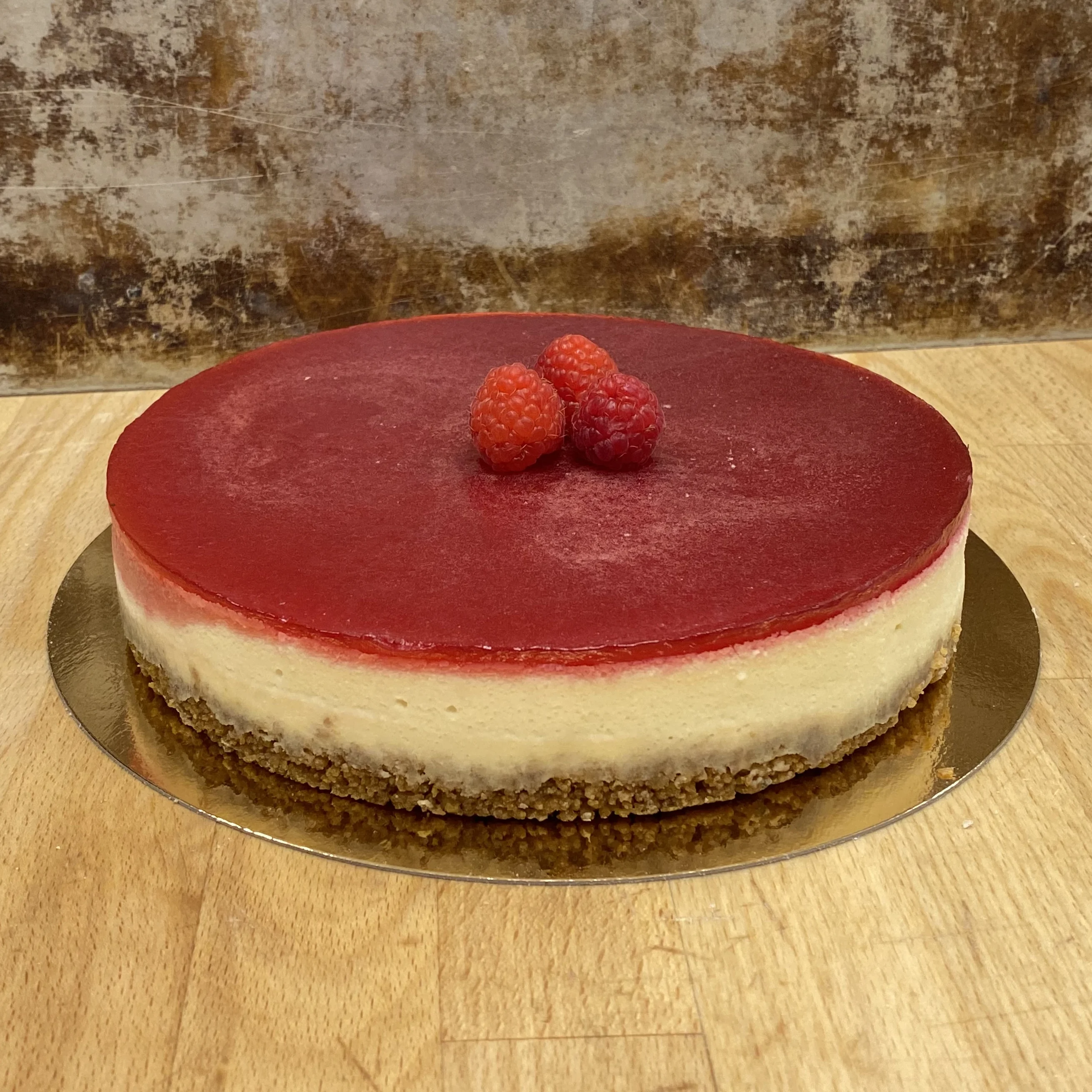 Cheesecake med hallongelé, dekorerad med hallon på toppen.