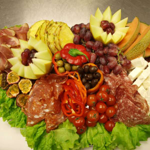 Medelhavsplanka med lufttorkad skinka och salami och frukt