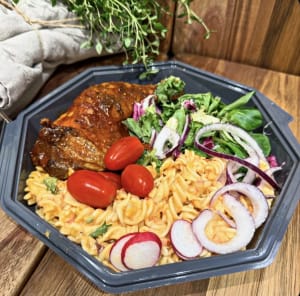 Tallrik med kycklingklubba, pastasallad och sallad