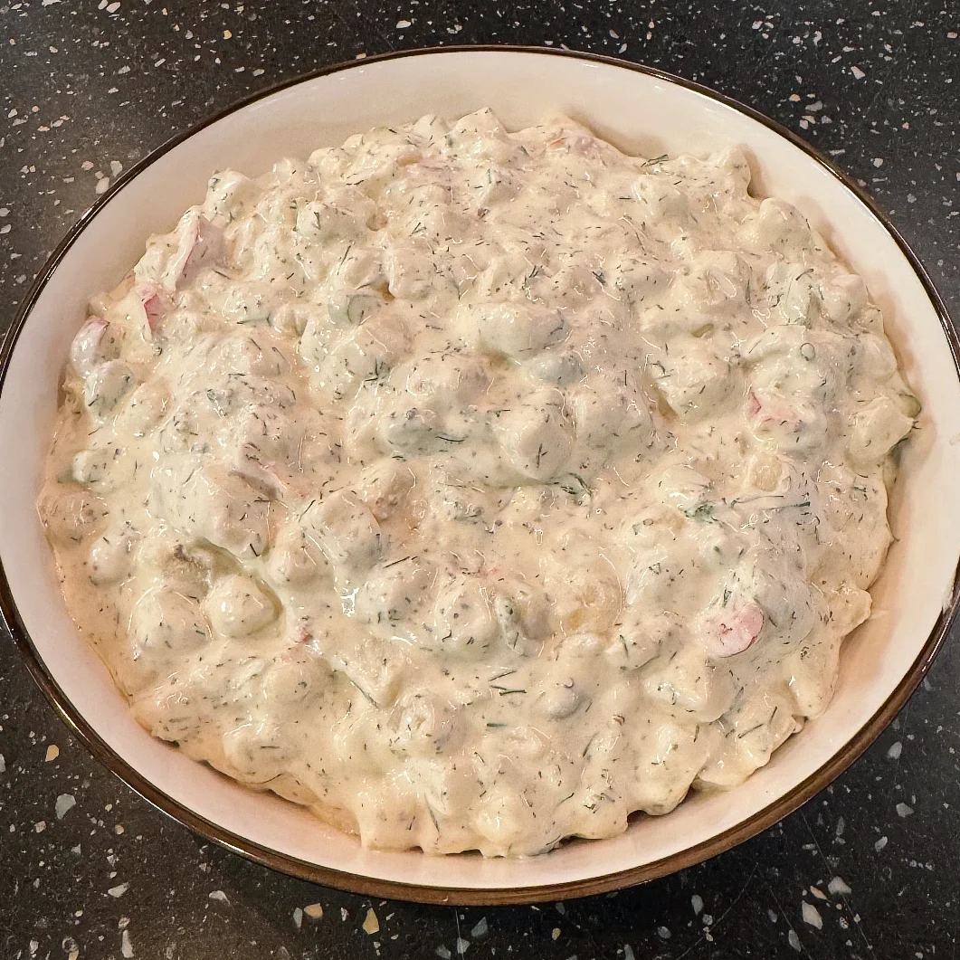 En skål med Potatissallad Deluxe, en krämig potatissallad med tärnad potatis, purjolök, paprika & kapris.