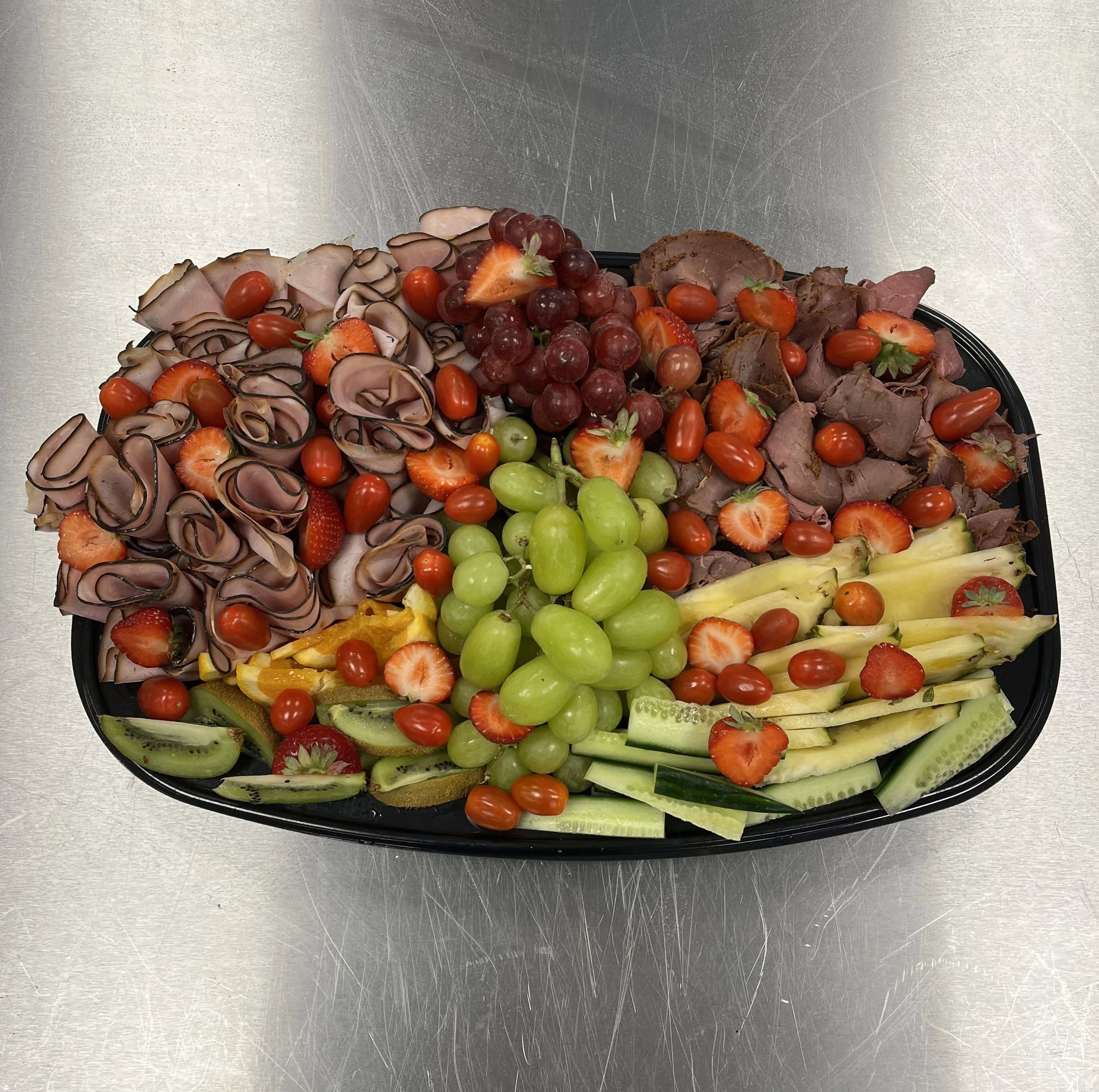 Festfat med rökt skinka, portvinsmarinerad rostbiff, vindruvor, ananas, jordgubbar, babyplommon tomater, gurka och kiwi.