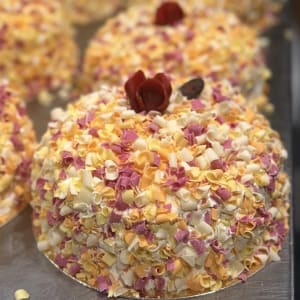Tårta dekorerade med färglatt chokladspån och röd ros