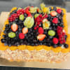 Fyrkantig frukttårta med grädde, täckt med mandelspån på sidorna och toppad med blåbär, hallon, jordgubbar, röda vinbär, physalis, vindruvor och mandarinklyftor.