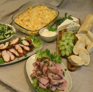 En buffé med två sorters kött, potatisgratäng, bröd och tillbehör