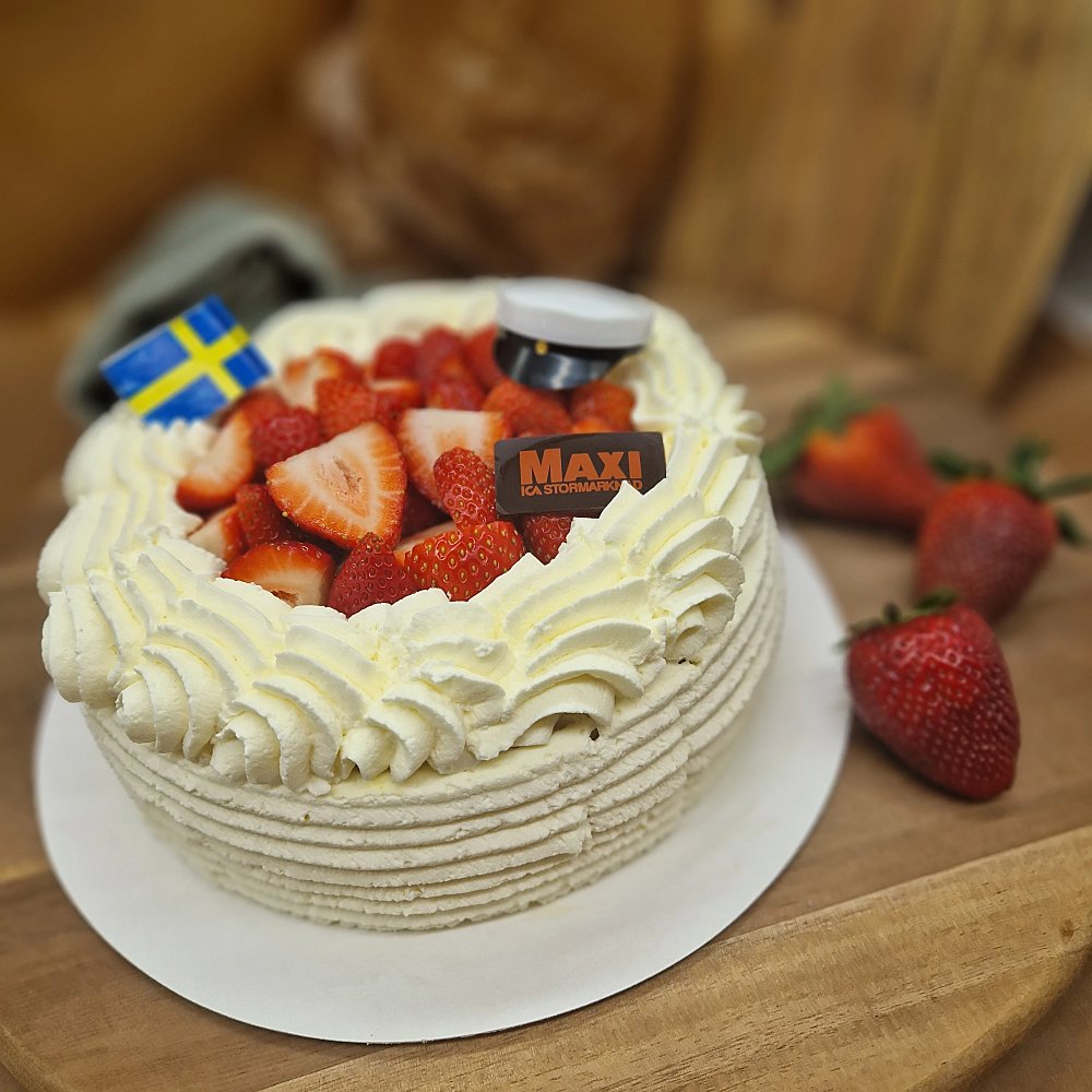 Jordgubbstårta med gräddrosetter, svensk flagg och studentmössa
