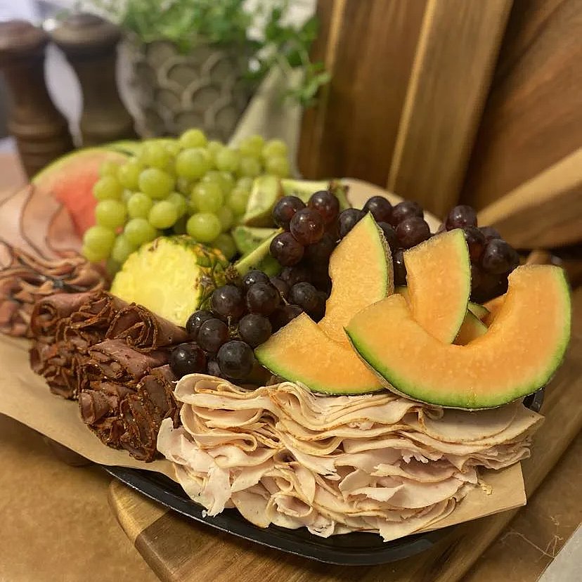 Festplanka med två sorter melon, vindruvor, ananas, grillad kyckling, rökt skinka och grillad rostbiff