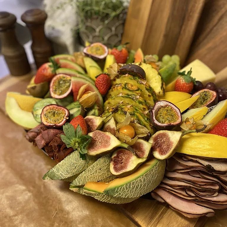 Planka fylld med massa exotisk frukt och chark samt potatissallad
