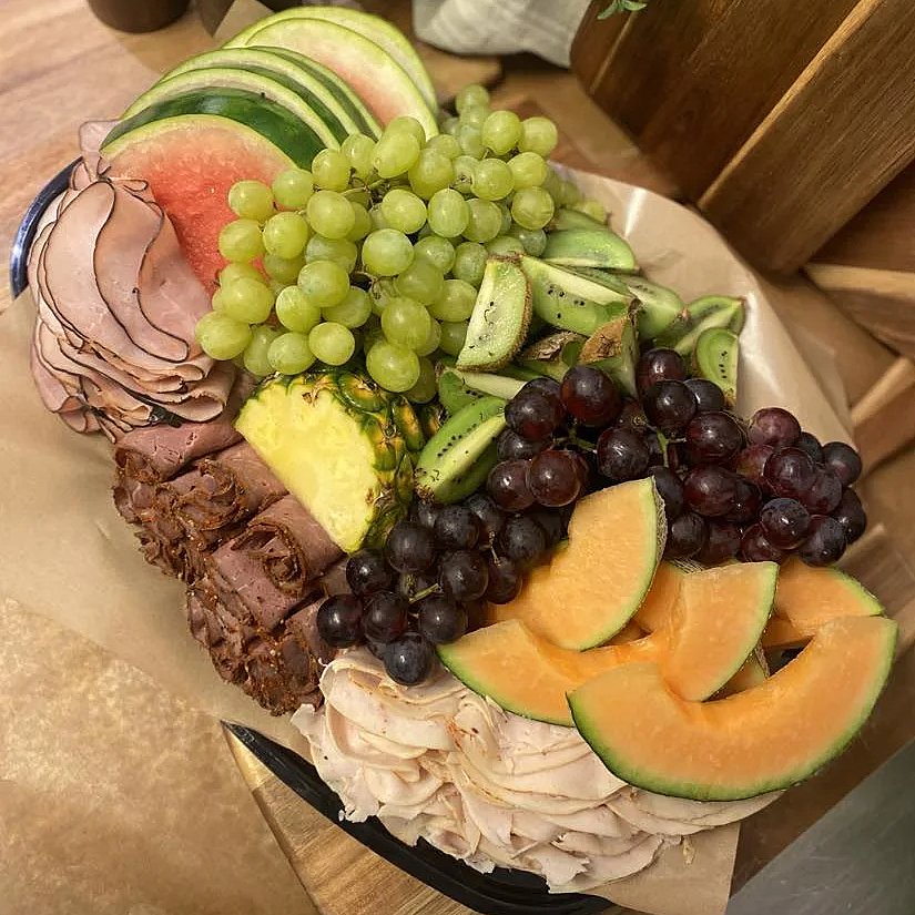Festplanka med två sorter melon, vindruvor, ananas, grillad kyckling, rökt skinka och grillad rostbiff