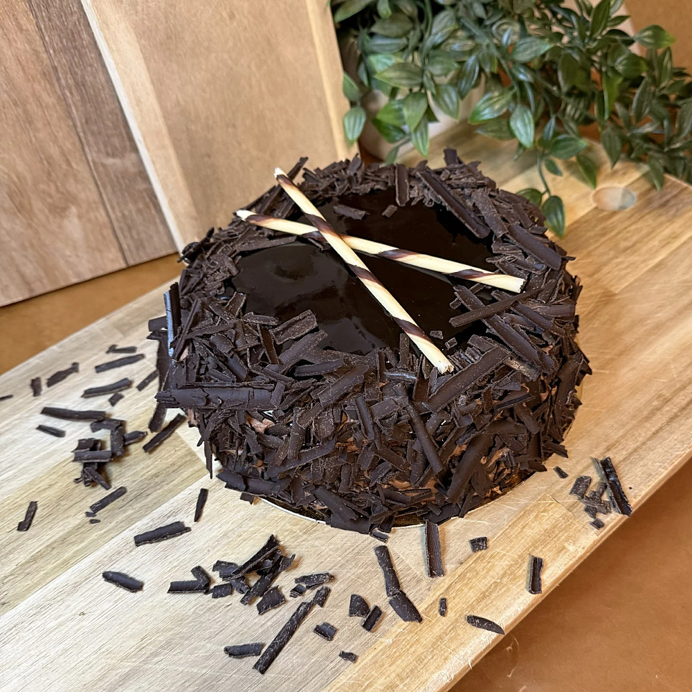 Chokladsockerkaka fylld med vaniljkräm och chokladgrädde. Toppad med en chokladspegel och mörka chokladflakes. Perfekt för den som älskar choklad!