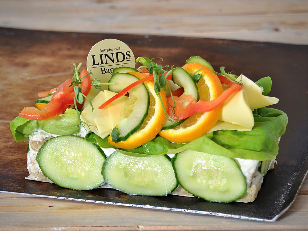Ett lager Vegansk mimosasallad och två lager röra med soltorkade tomater, veg. Majonäs, rödlök, grönsaker o kryddor. Franskbröd som botten, dekorerad med vegansk ost, frukter och grönsaker. (Innehåller ej: Fläsk, skaldjur, mjölk och ägg.)