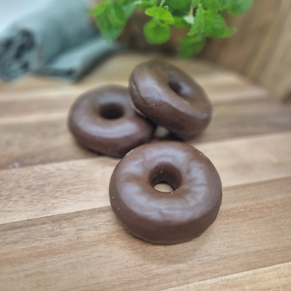 Chokladdoppade donuts på träbricka. Fika på fikabord