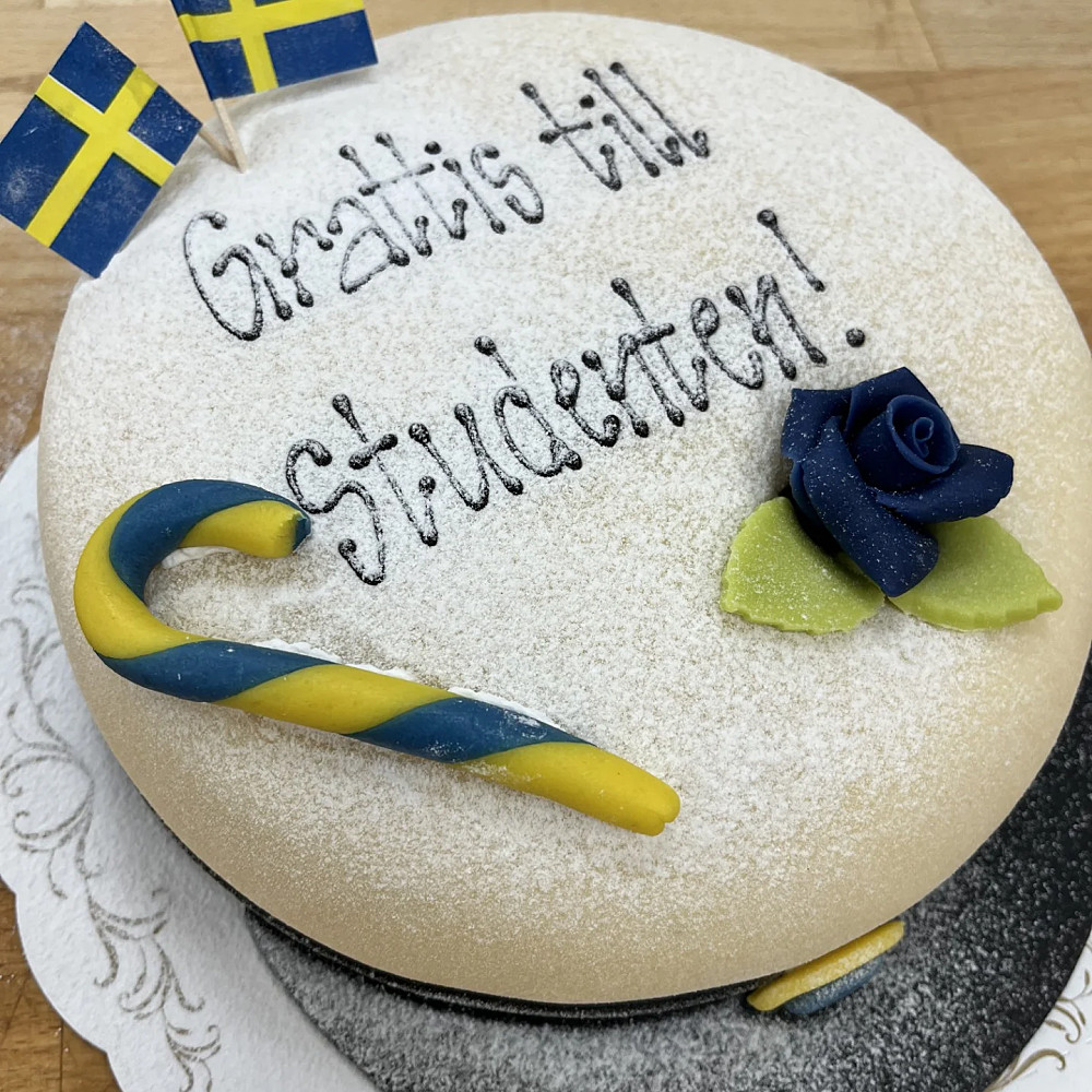 Studentmössa med text, ros och flaggor