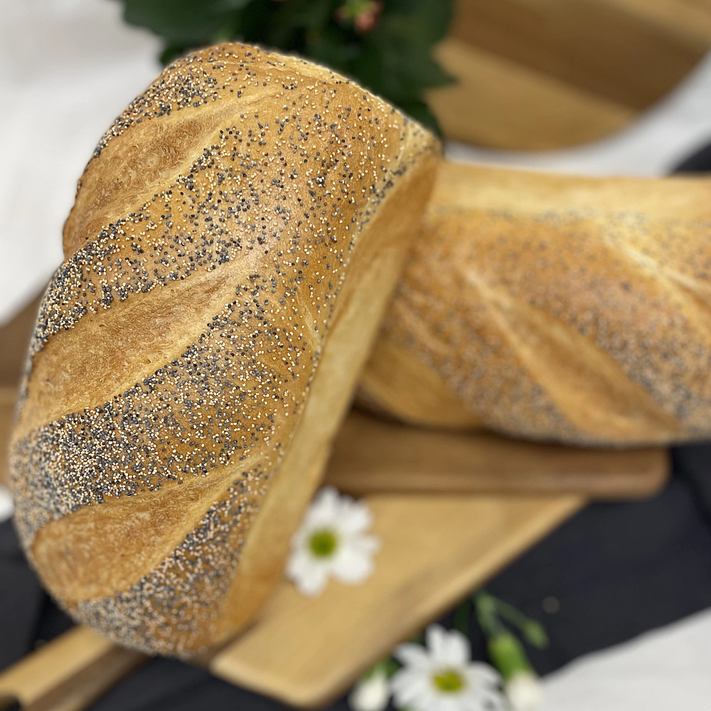 Ett ljust bröd bakat i form, toppat med vallmofrö.