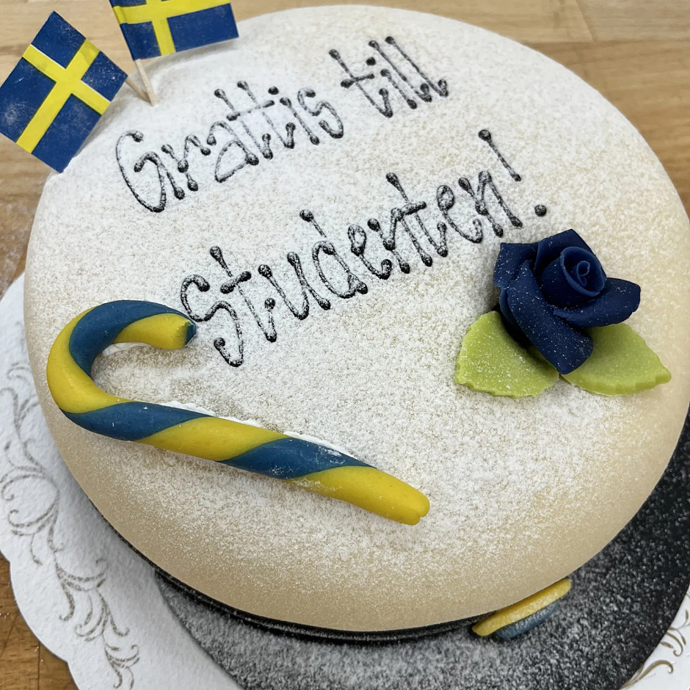 Studentmössa med text, ros och flagga