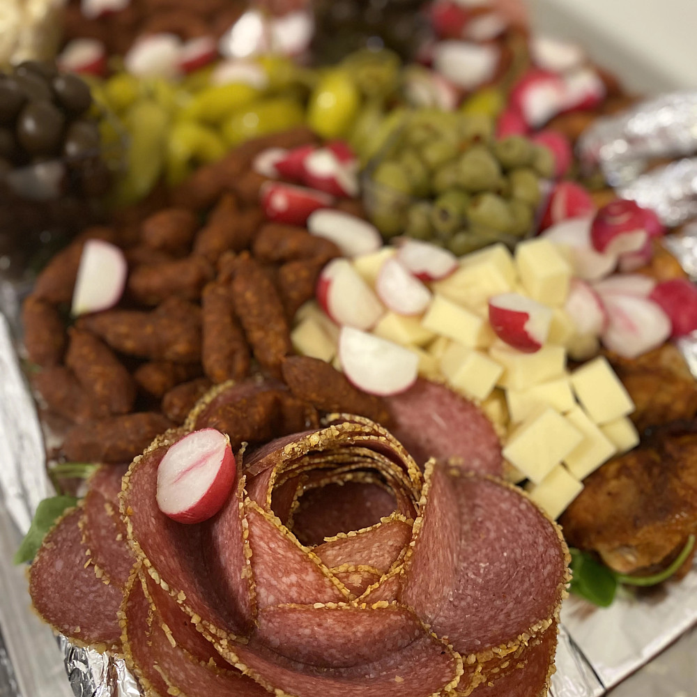 En bricka med en blandning av olika salami, ölkorv, oliver, ost och kycklingben