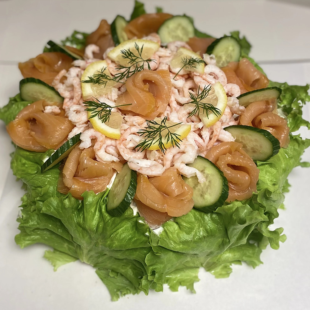 Smörgåstårta med kallröktlax och räkor. Sallad på sidorna. Garnerad med citron och dill.