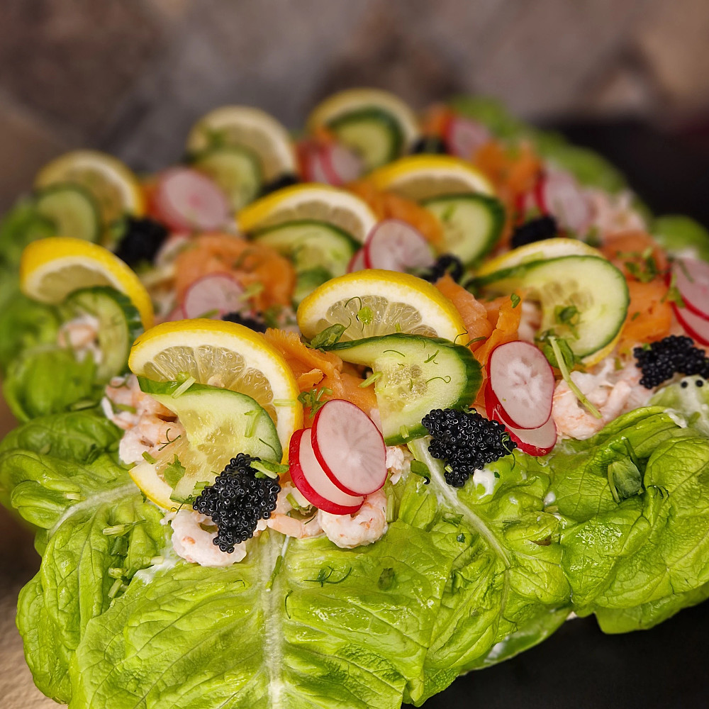 Närbild på smörgåstårta och handskalade räkor, kallrökt lax, citron, gurka, stenbitsrom, gurka, rädisa samt krispig sallad,