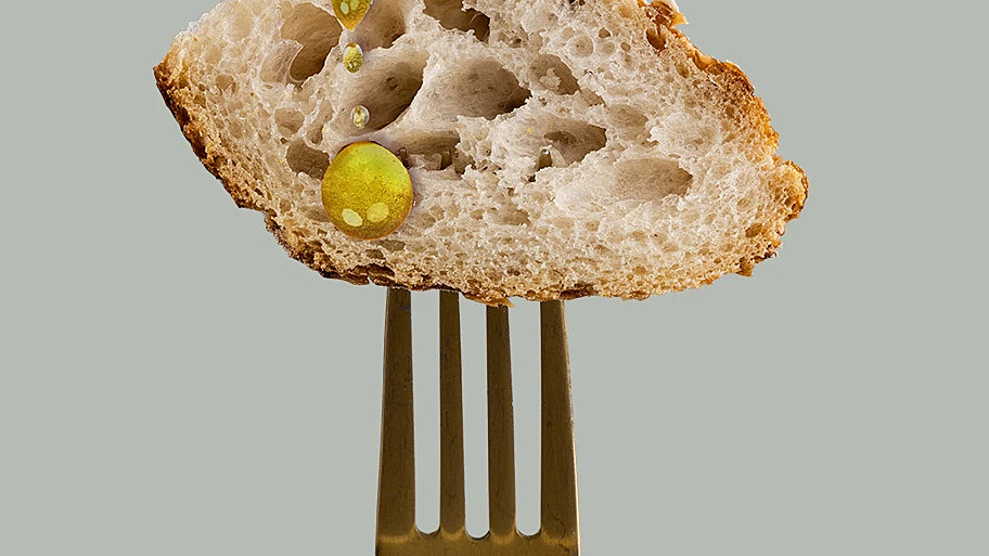 En skiva bröd på en gaffel. Gul bakgrund.