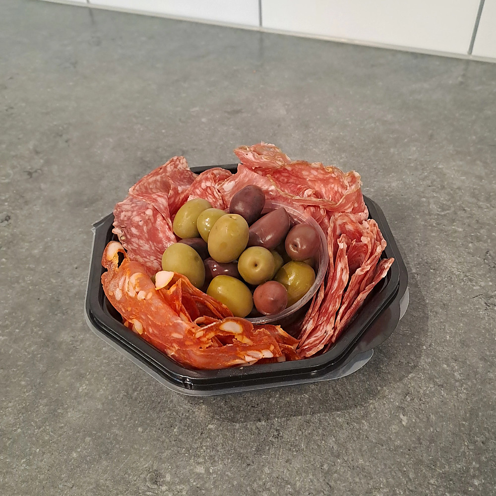 bricka med milanosalami, tryffelsalami, ventricina piccante, magnificosalami och oliver i en skål i mitten