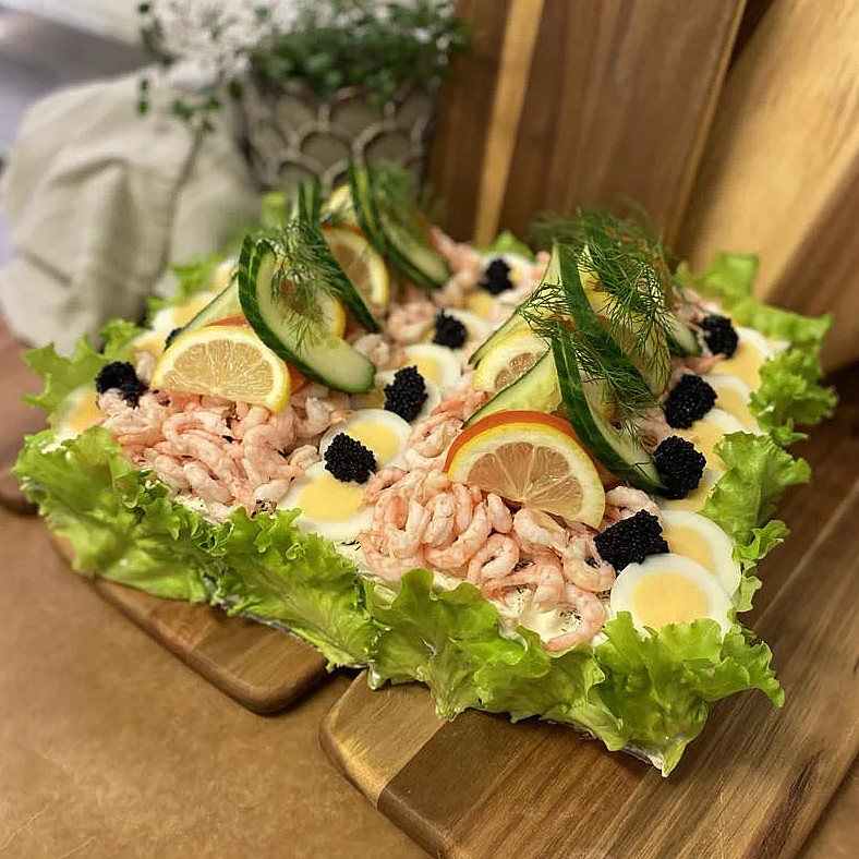 Smörgåstårta toppad med räkor och ägg.