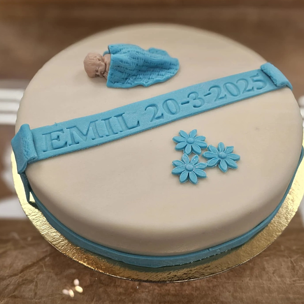 Här har ni en doptårta som innehåller vaniljkräm, hallonsylt, och grädde med marsipanöverdrag. Och text ingår i priset