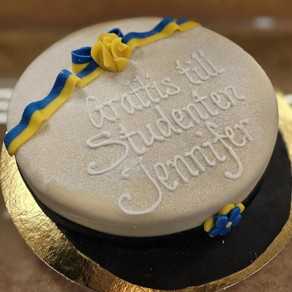 Studenttårta med text gjord på hallonsylt, vaniljkräm, grädde och täckt med marsipan.