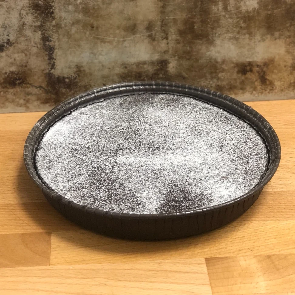 En butiksbakad kladdkaka i form på 600g toppad med florsocker.