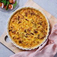 En nygräddad paj i pajform ligger på en skärbräda.