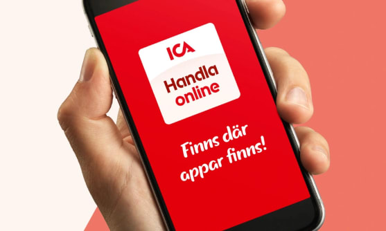 En hand håller upp en mobiltelefon med appen Handla online på skärmen.