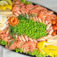 stort serveringsfat med kallrökt lax i rullar, ärtor och dekorerat med räkor, ägg, grönsaker