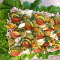 En sallad med grönsaker, ägg och räkor serveras på ett fat.