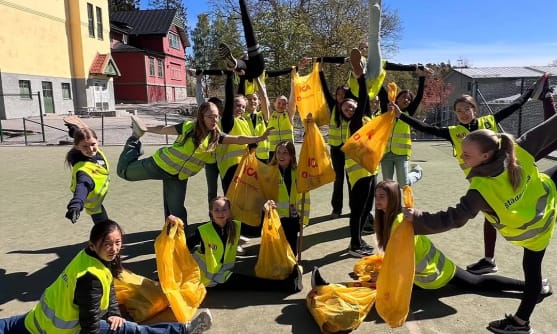 Flera personer står tillsammans utomhus på marken och håller i väskor.